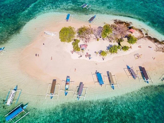 Luftaufnahme einer winzigen Insel mit Auslegerbooten, die am Strand vertäut sind.
